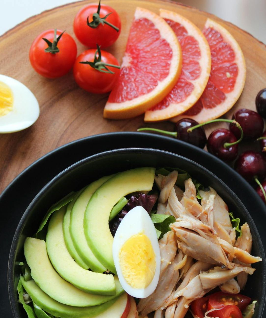 Assortment of healthy food: tomatoes, grapefruit, cherries and avocado bowl.