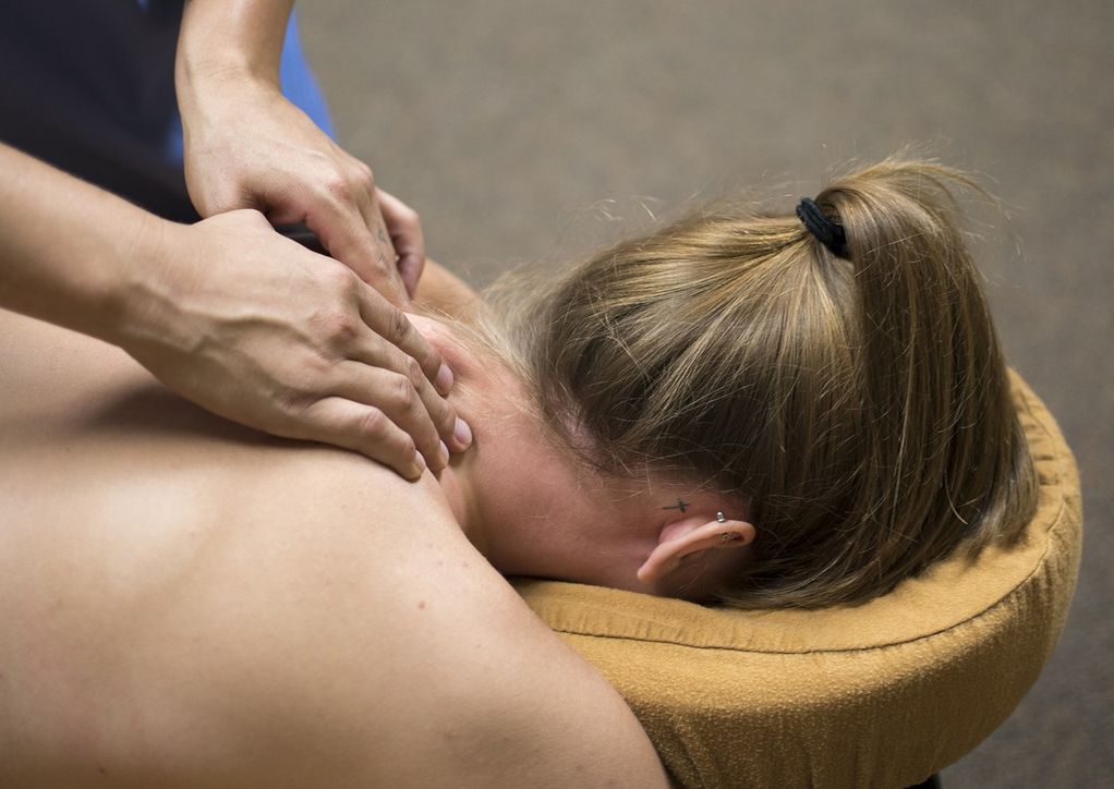 A woman receiving a neck passage with her head in a proper massage bed.