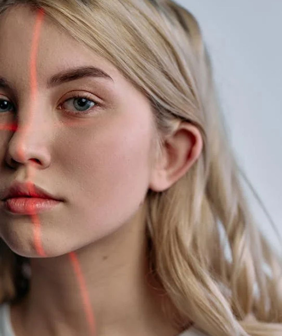 Woman receiving a thermography scan, red light shown on her face.